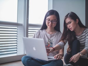 two girls looking at laptop screen and one pointing at screen